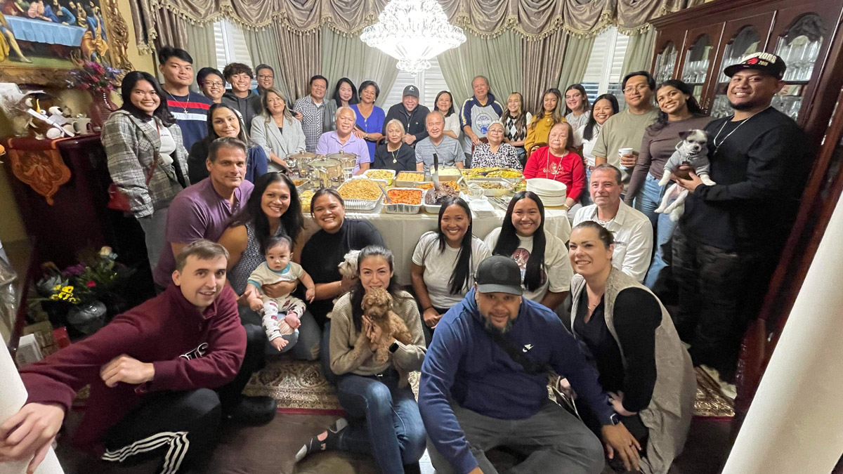 A large family gathered around a dining table full of food.