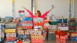This cover image features a staff from The Ottawa Shoebox Project and shows her sitting among a pile of gift-filled shoeboxes they collected.