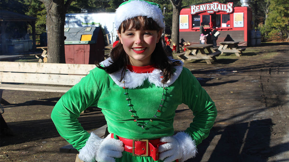 A young woman dressed as an elf smiles at the camera