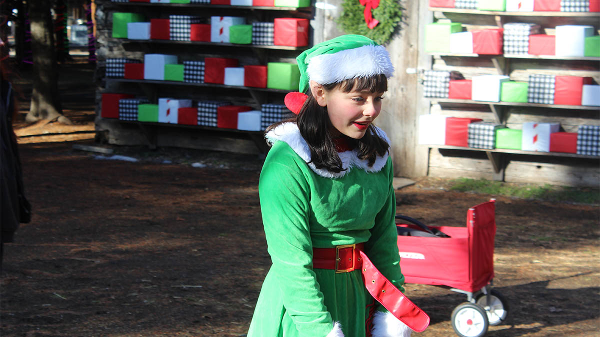 A young woman dressed as an elf smiles towards something off Carter