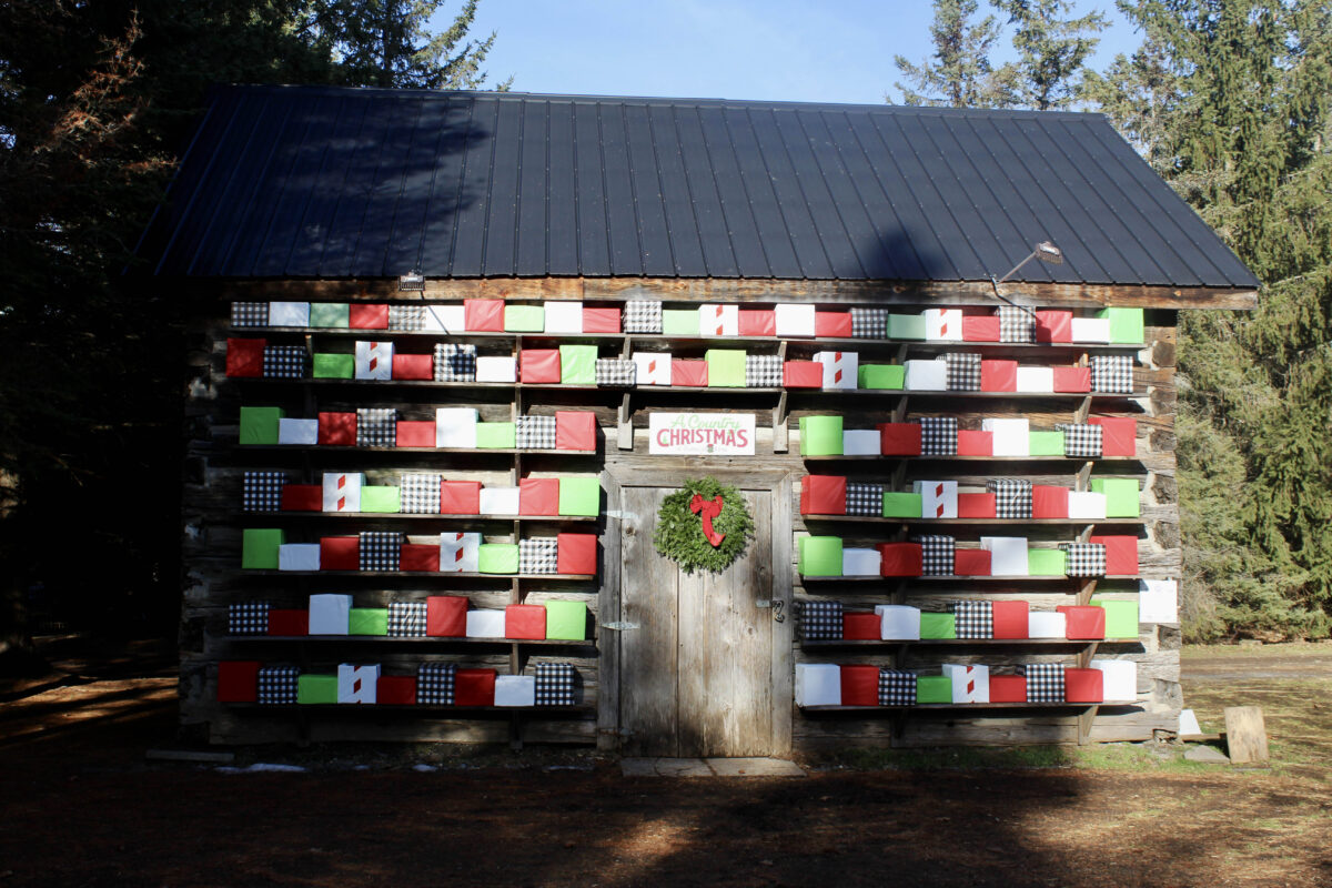 A log structure is decorated with rows and rows of Christmas presents decorated in red, green, white and black. 