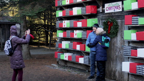 A couple posed for a photo in front of the colourful wall of Christmas presents at Saunders Farm in rural southwest Ottawa near Munster during the November opening weekend of A Country Christmas. [Photo © Alyshia McCabe]