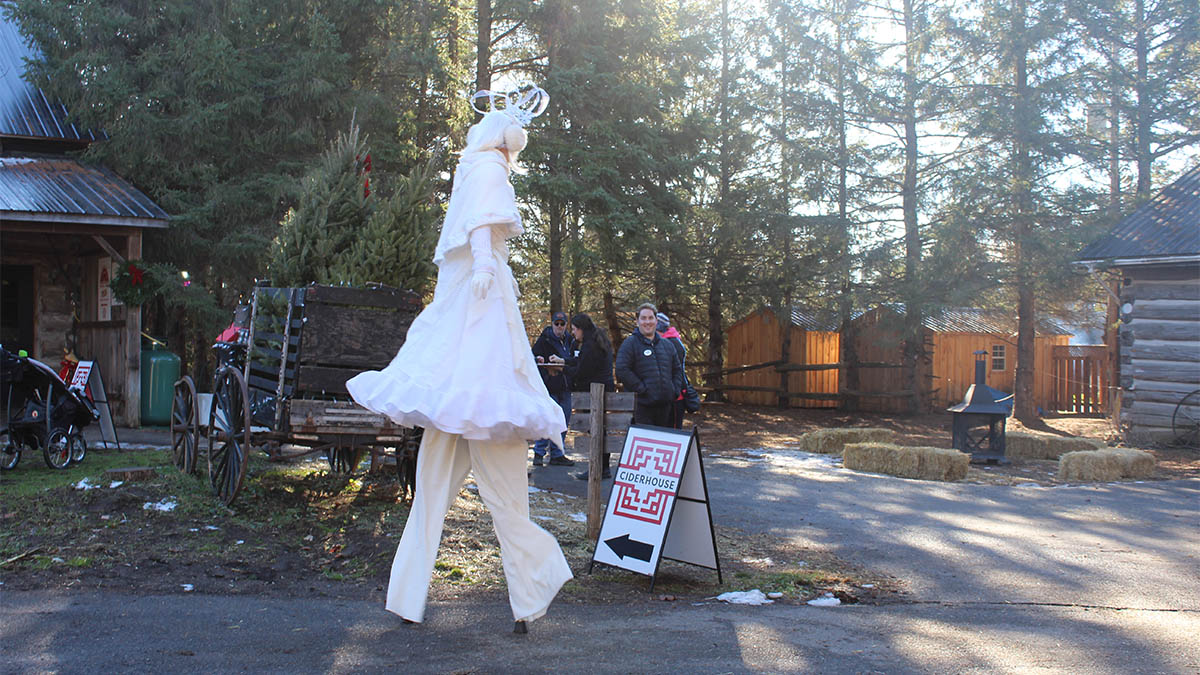 a stilts performer dressed in all white walks by