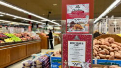 The image shows the poster of Christmas meals offered by Farm Boy this season. The photo was taken inside a Farm Boy. There was someone buying things in the background.