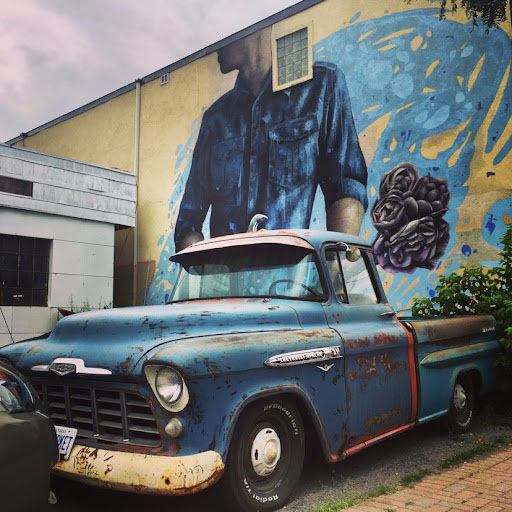 A mural of a person wearing a collared shirt. A truck blocks half of the mural.