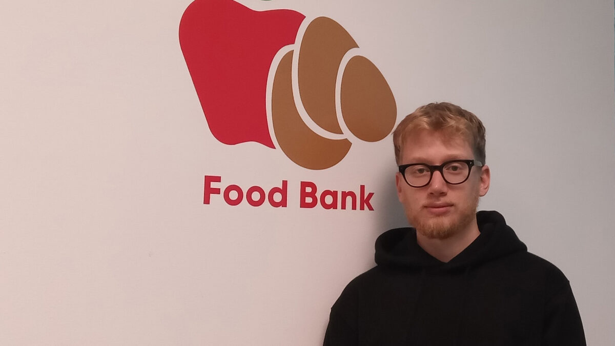 A man standing on the wall beside the food bank sign at the University of Ottawa.