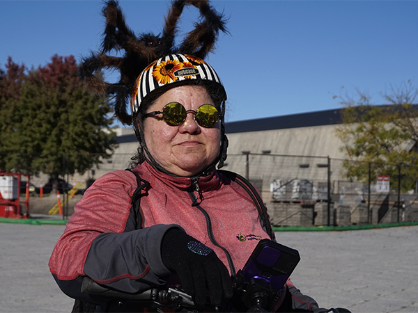 A woman wearing a bike helmet with a fake spider attached on top.