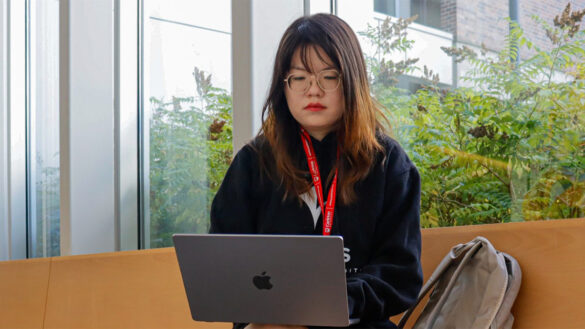 A student is seen using her laptop in Richcraft Hall at Carleton University.
