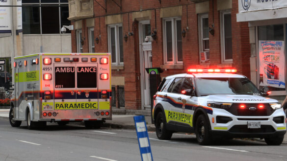 Two paramedic vehicles on a street with flashing lights.