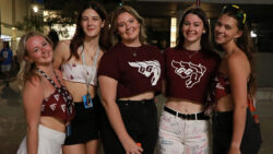 Five girls stand next to each other wearing white and burgundy University of Ottawa Gee-Gees merch.