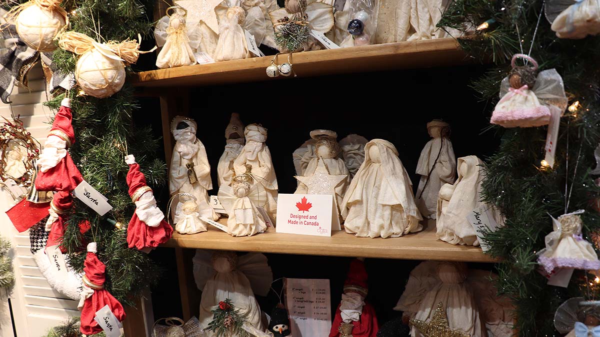 A display of handmade figurines on sale at the Nepean Sportsplex Christmas Market. There are handmade angels, Santas and other holiday figures on display.