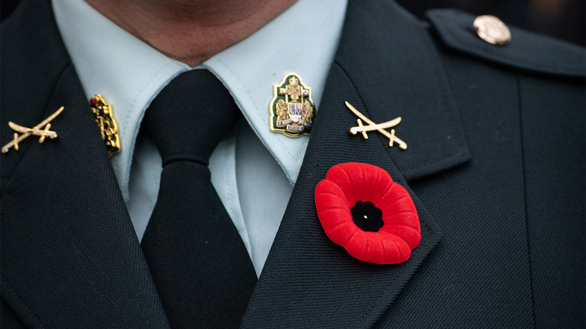 A red poppy is shown on the lapel of a Canadian Army uniform