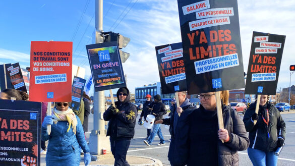 Health-care workers hold signs on the picket line at Gatineau Hospital as they walk on the street.