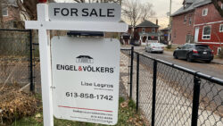 A white for sale sign for Engel & Volkers hangs in a yard.