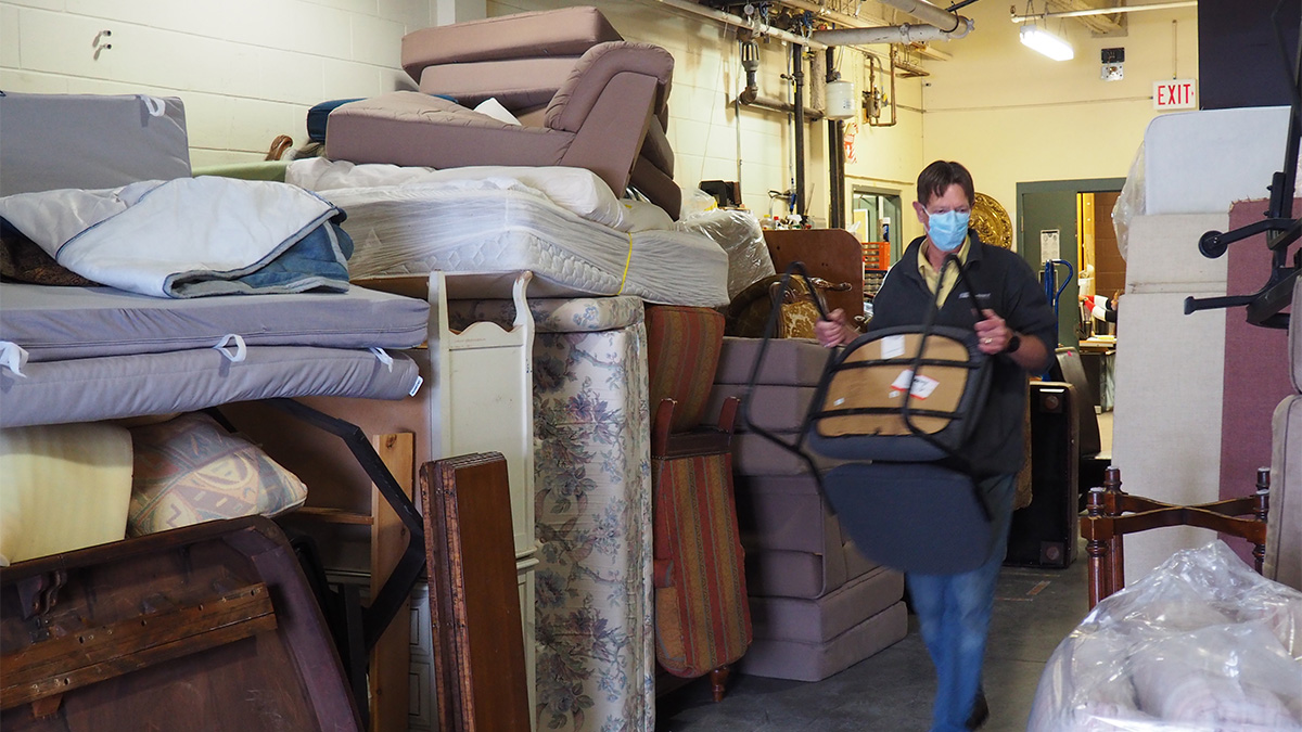 A volunteer moves a chair in a furniture storage facility.
