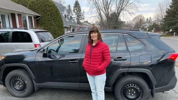 Wendy Bladin stands in a red jacket and blue jeans in front of her black 2022 Toyota Rav4 car parked in her driveway in Barrhaven.