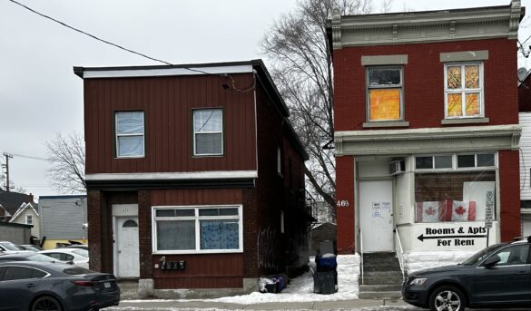 Two red brick buildings sit side by side, sign in one that says "Apartments for Rent".