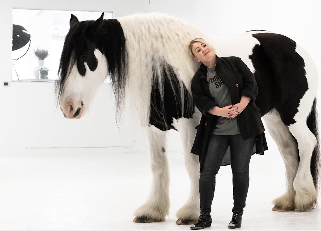 Photo shows singer Jann Arden with big black and white horse