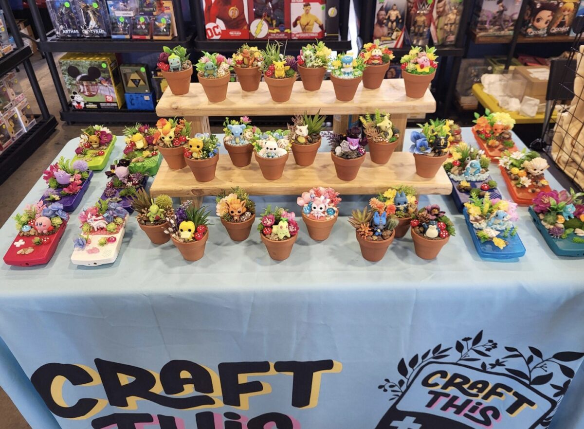 table at collectibles convention covered with little plant pots full of fake flowers and figurines from video games