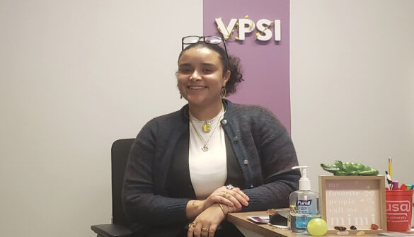 Smiling woman sits at desk with VPSI sign on wall -- vice-president of student issues at Carleton