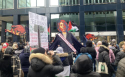 large crowd of protesters assembled outside downtown Ottawa office building with large sign criticizing Israel, the Canadian government over attacks on Gaza. Effigy at centre of picture shows foreign minister Mélanie Joly