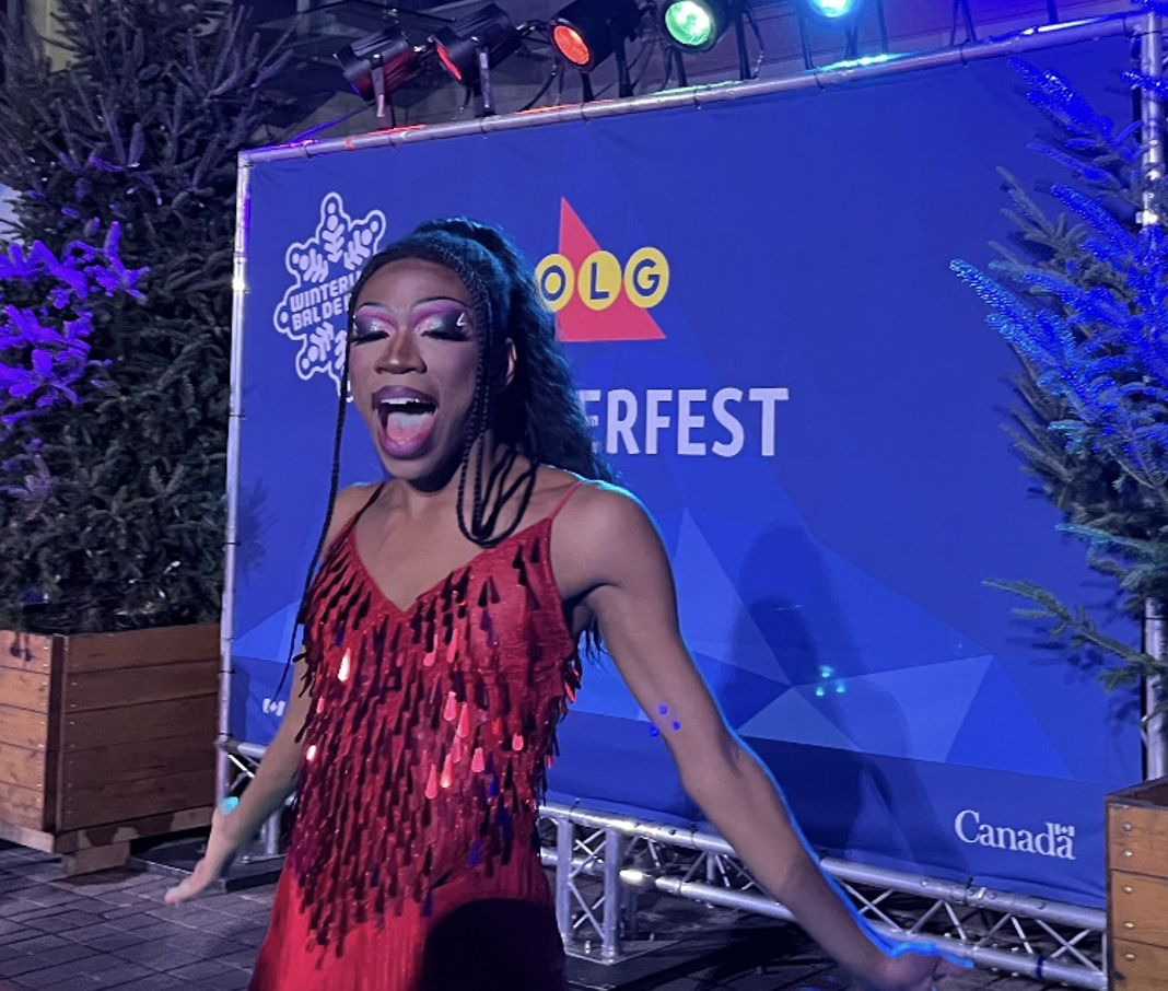 Drag performer singing on stage in front of Winterlude sign