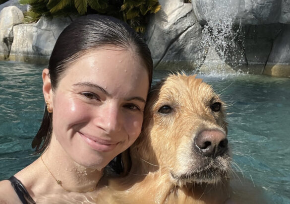 Smiling woman in pool with her dog, a white lab