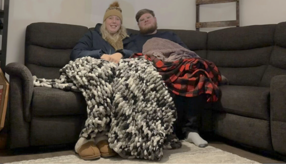 Kendra Adams and Jackson McCully sit in their home in Gatineau with full winter gear on. The couple turn down the heat during the day to save money. [Capital Current Zoom screen capture]