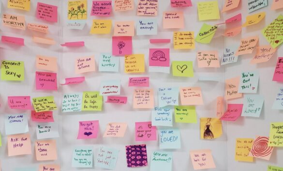 A series of sticky notes carrying messages of support for sexual assault victims stuck on a white background.