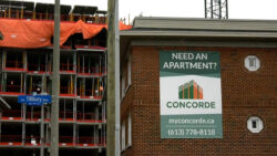 Photo shows an older rental building, with brand new condos being built in the background.