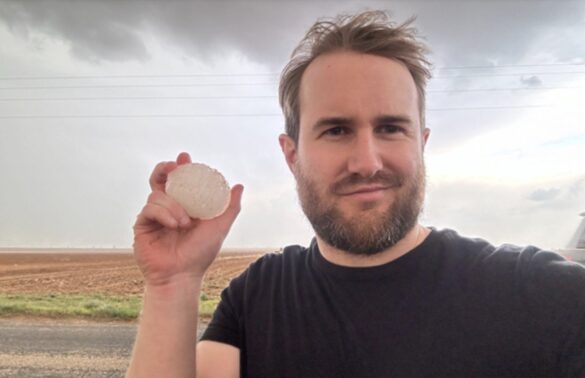 Bearded young man holds hail stone as big as a golf ball