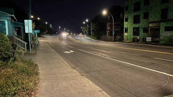 Empty street during the night with one car's headlights in the distance