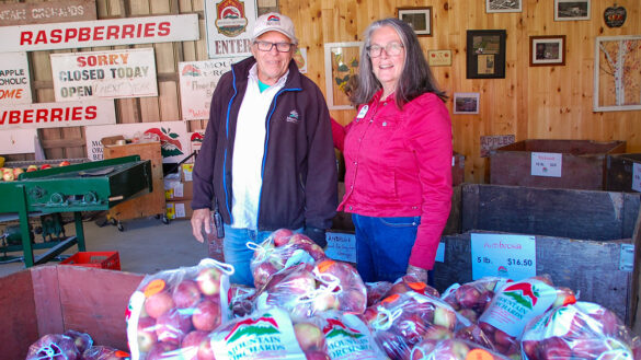 Shelley and Phil Lyall standing in front of a pile of bagged apples.