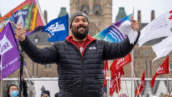 Alex Silas stands in front of a labour rally on Parliament Hill. In May 2024, he was elected as PSAC's National Executive Vice-President.