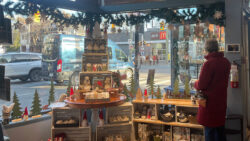 The Papery's window display from the inside, with Christmas-themed trinkets and products along the glass with a person browsing.