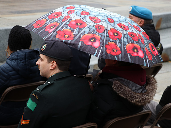 A poppy umbrella over a Canadian Armed Forces member. 