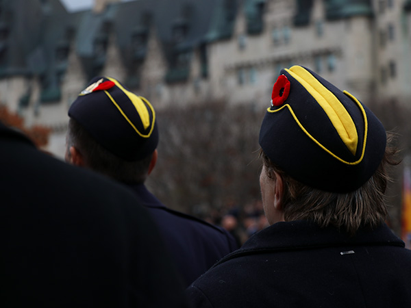  Two members of the Canadian Armed Forces wearing hats with poppies. 