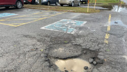 Photo of a pothole in front of an accessible parking space.