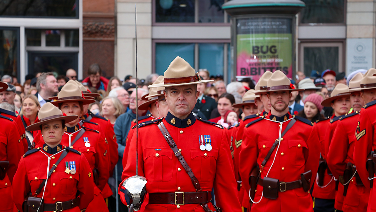 RCMP standing in formation in front of a large crowd of people. 