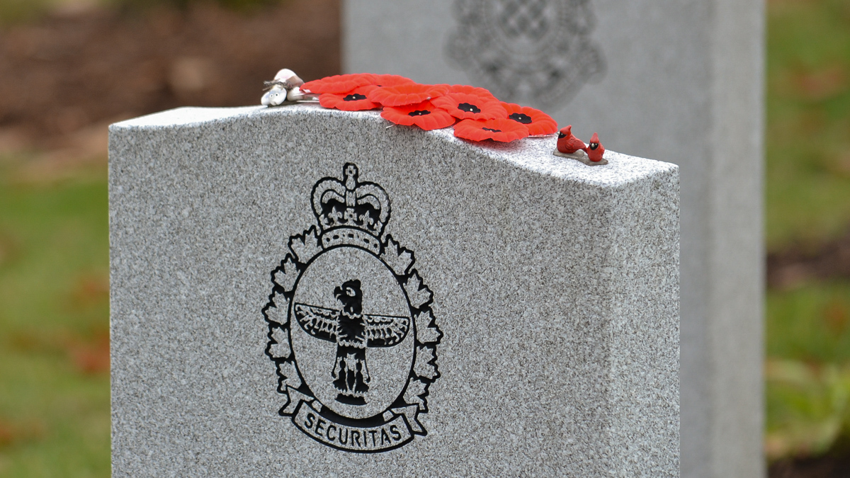 Two miniature cardinal figurines sit atop a military headstone.