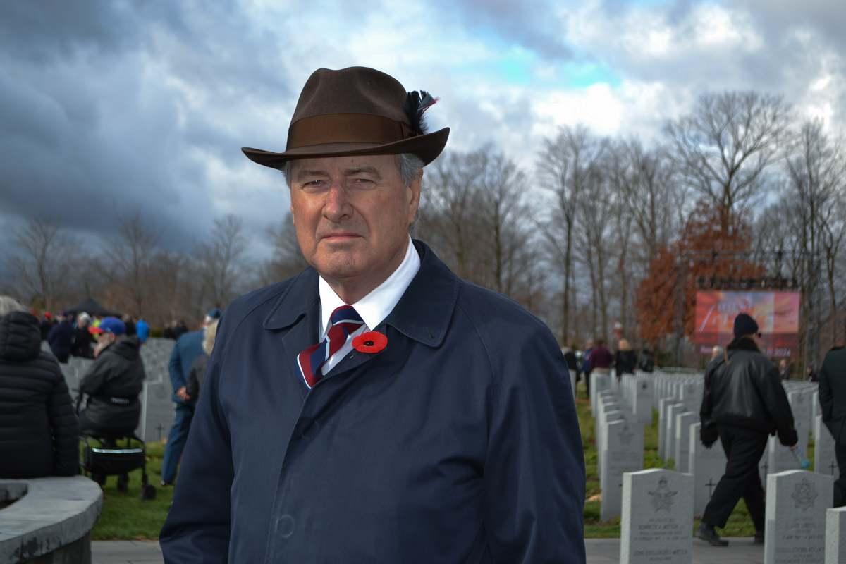 A man wearing a brown hat with a feather looks at the viewer.