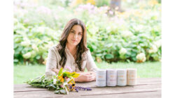 Woman sitting on bench at a park with a bouquet of flowers and her tea products in front of her