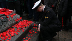 Solider Kneeling in front of the Tomb of the Unknown Solider, covered in poppies.