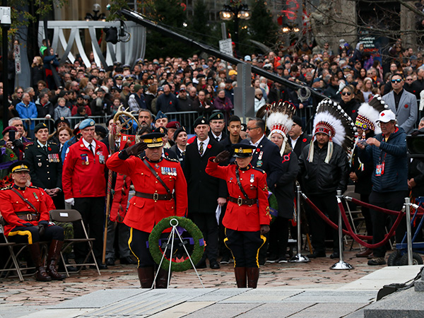 Two members of the RCPM saluting wreaths, in front of a large crowd.  