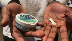 A young man holds a tin of mint flavoured Zonnic nicotine pouches.