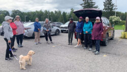 Nine members of the Ottawa Voyageurs Walking Club are gathered in a parking lot before one of their walks. [Capital Current photo]