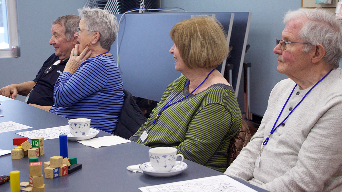 Four attendees of the memory cafe laugh and listen as they talk about memories from their childhood. 