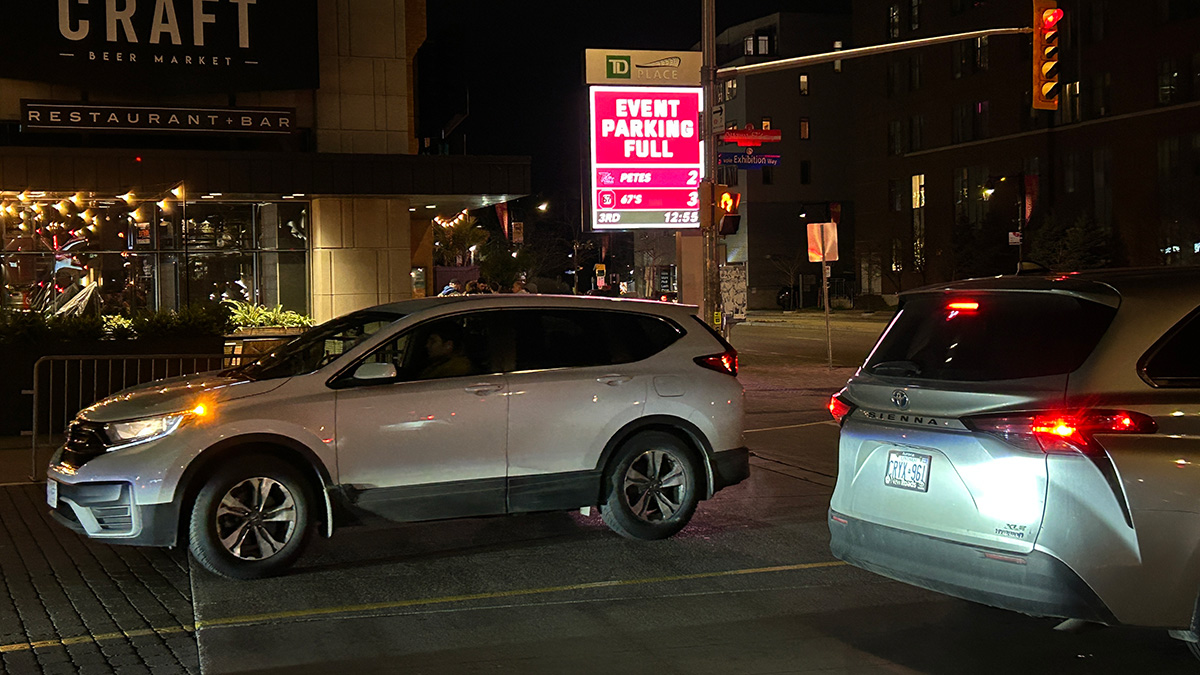 Cars at an intersection at Lansdowne park. Digital sign next to the road reads "EVENT PARKING FULL."