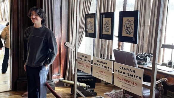 Young man stands in front of three paintings.