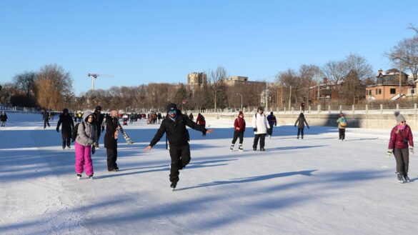 Skaters glide down the Rideau Canal on a sunny day.